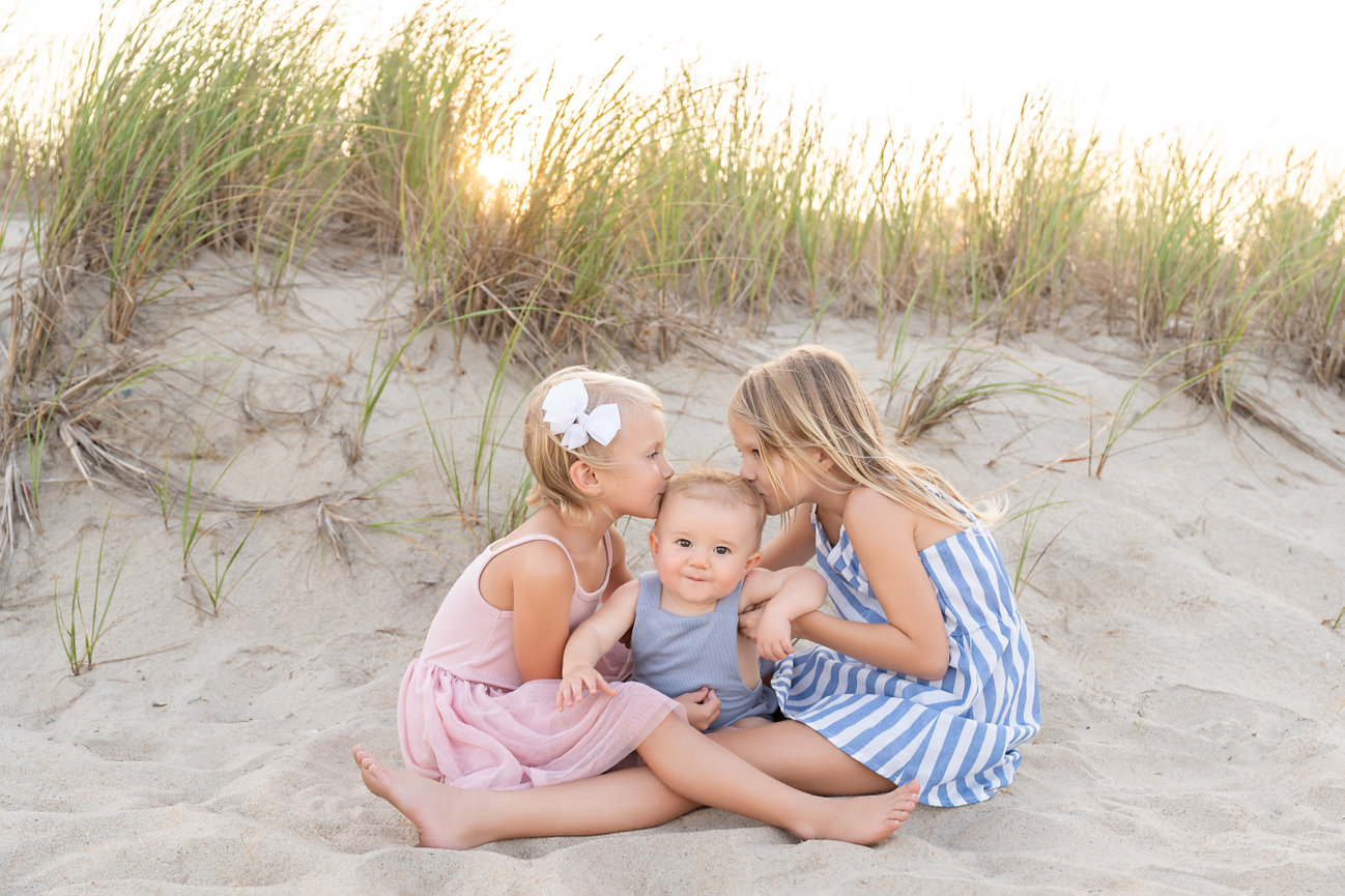 Big sisters hugging little brother during golden hour on the beach