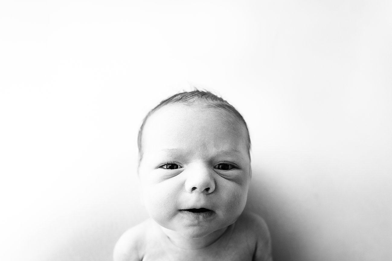 Candid newborn image in black and white, highlighting expressive face and early personality traits
