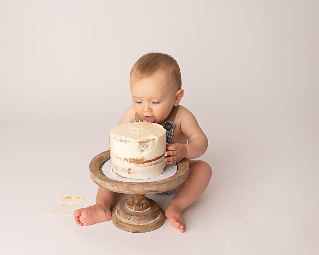 One-year-old taking first bite during minimalist cake smash session in Sea Girt NJ