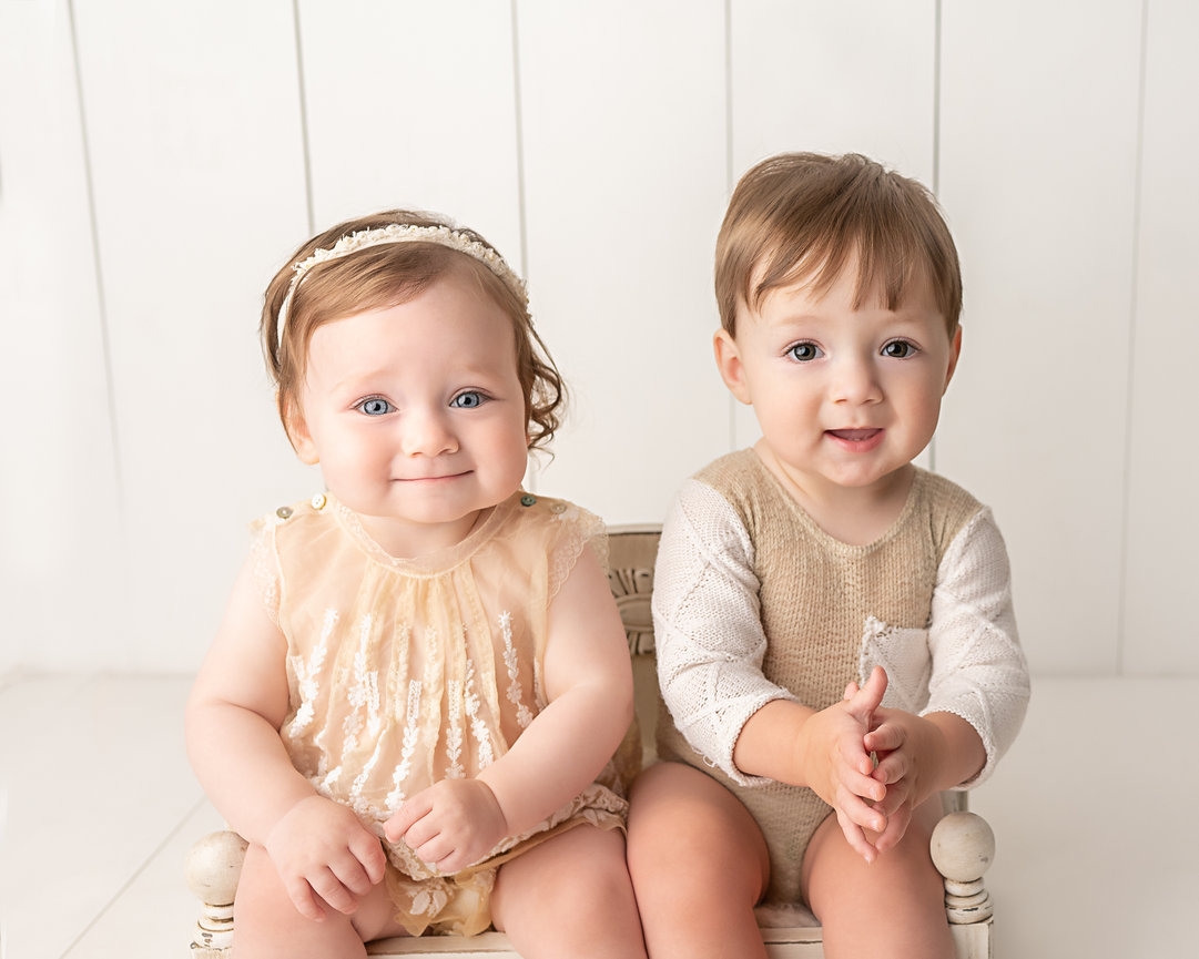 Twins celebrating first birthday on modern white set with simple, organic props and natural smiles in Cranford, NJ