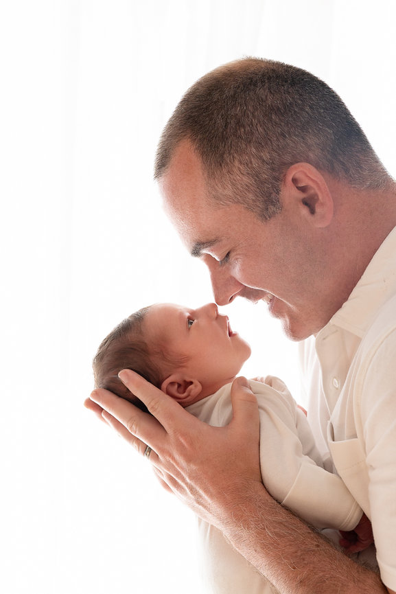 Tender nose-to-nose family moment on against sheer white backdrop