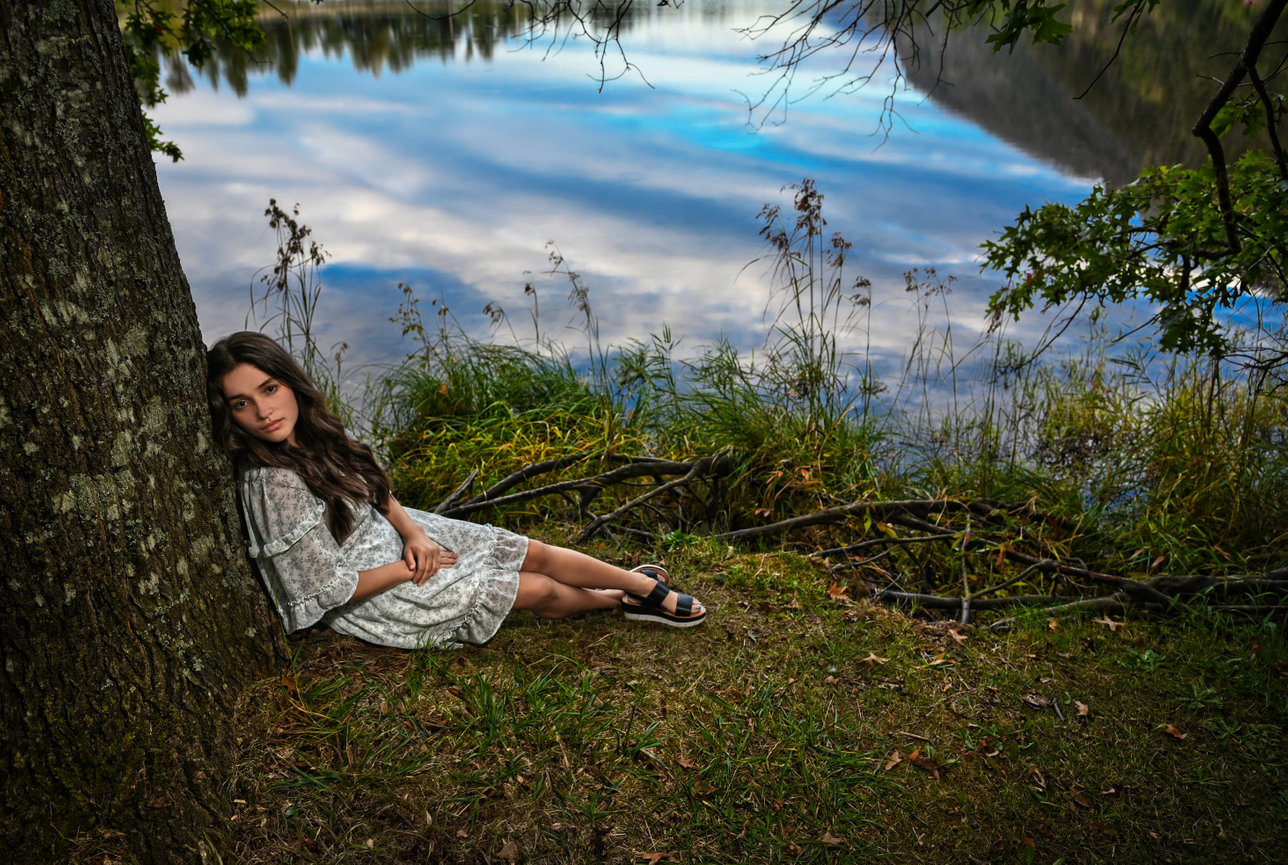 Woman reclining on a grassy ledge with a view of the sky below.