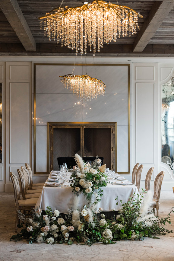 Elora mill reception decor, ballroom wedding table decor with cream chairs neutral flowers and modern chandeliers.