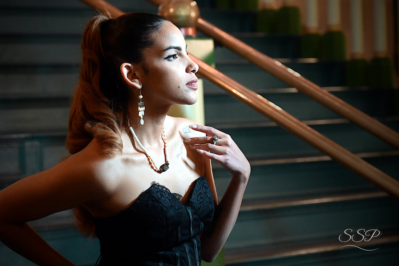 Portrait of a woman in a black dress standing near stairs with dramatic light