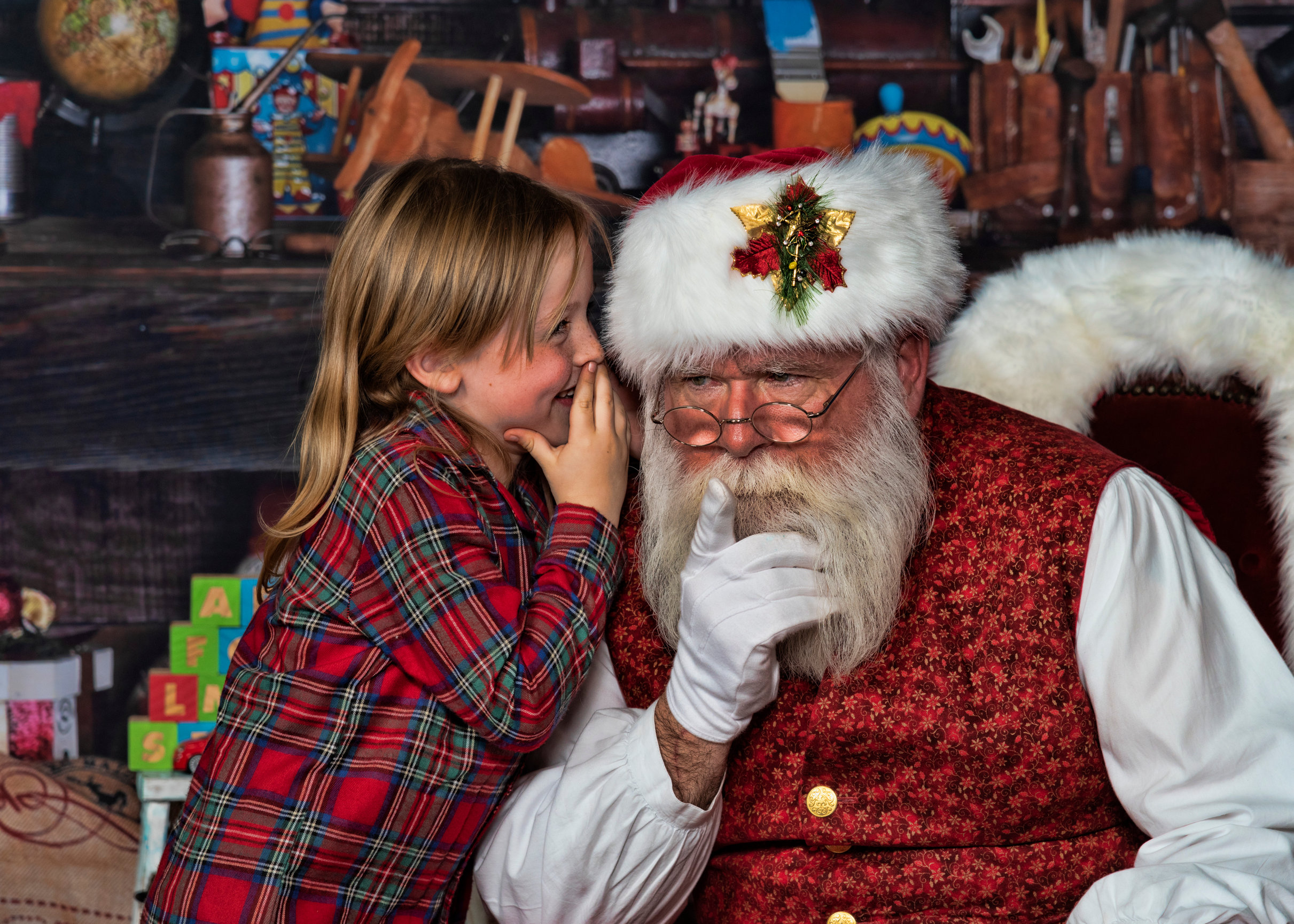 Little boy whispering into Santa's ear