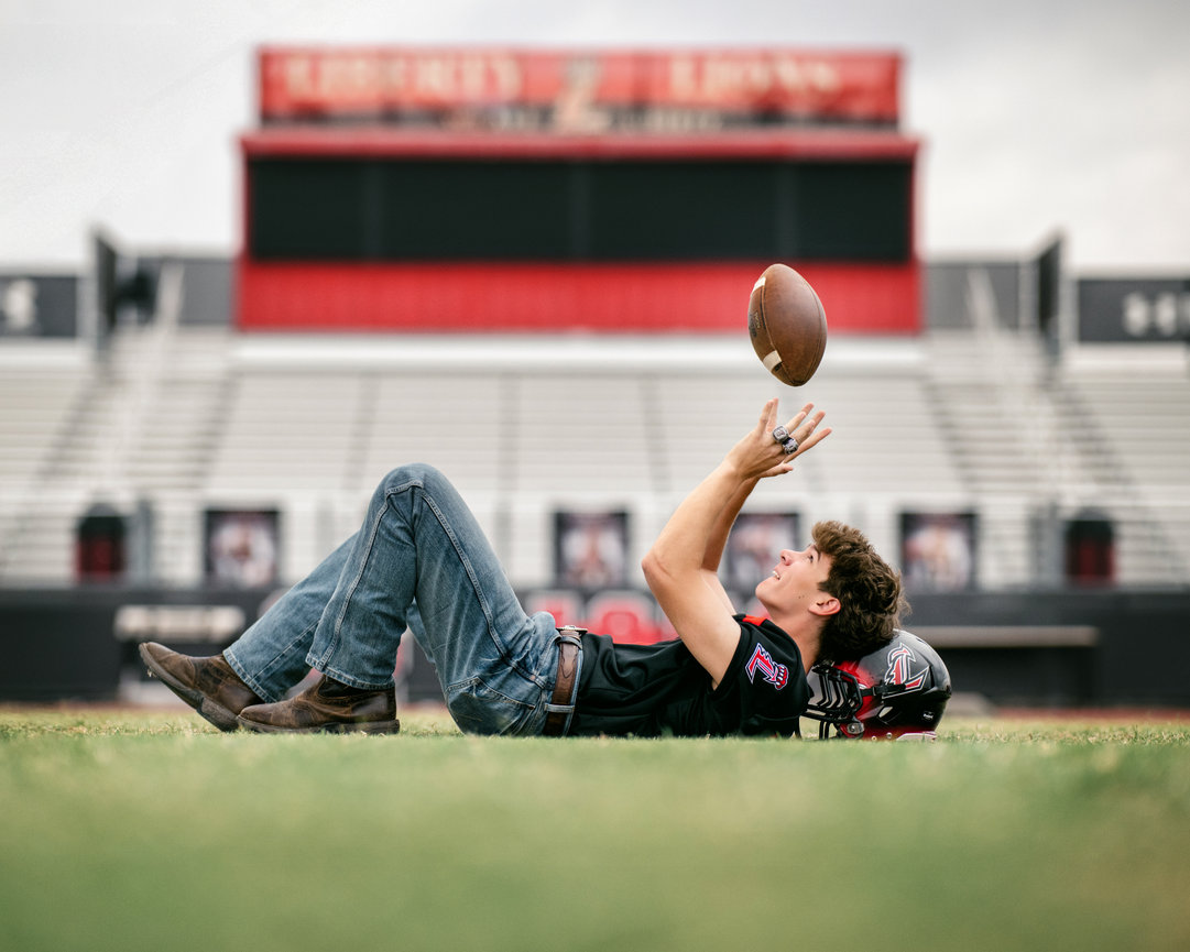 High school senior football player lying on field with helmet