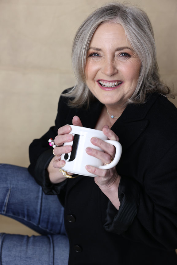 Smiling gray haired woman holding a white mug in a casual studio portrait. personal branding photos Melbourne