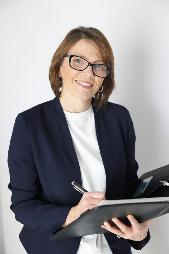 Smiling woman in glasses taking notes on a clipboard against a white background. authentic photos for my business and website