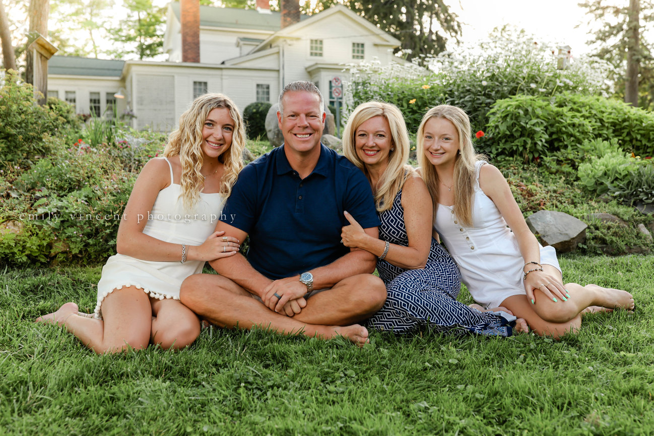 Family of four seated on blanket during outdoor photo session in Farmington, MI