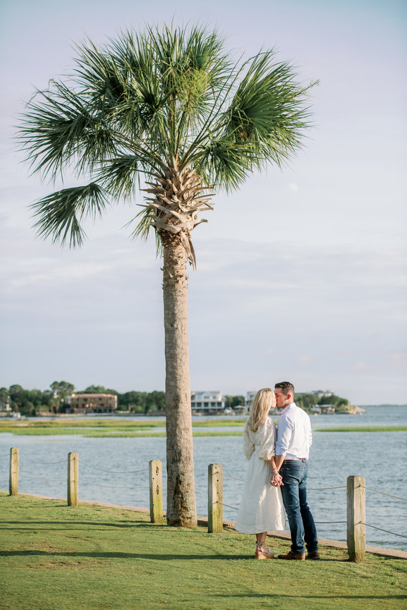 Couple kissing by the water in Mount Pleasant area of Charleston, South Carolina. Engagement photography by Heather Durham.