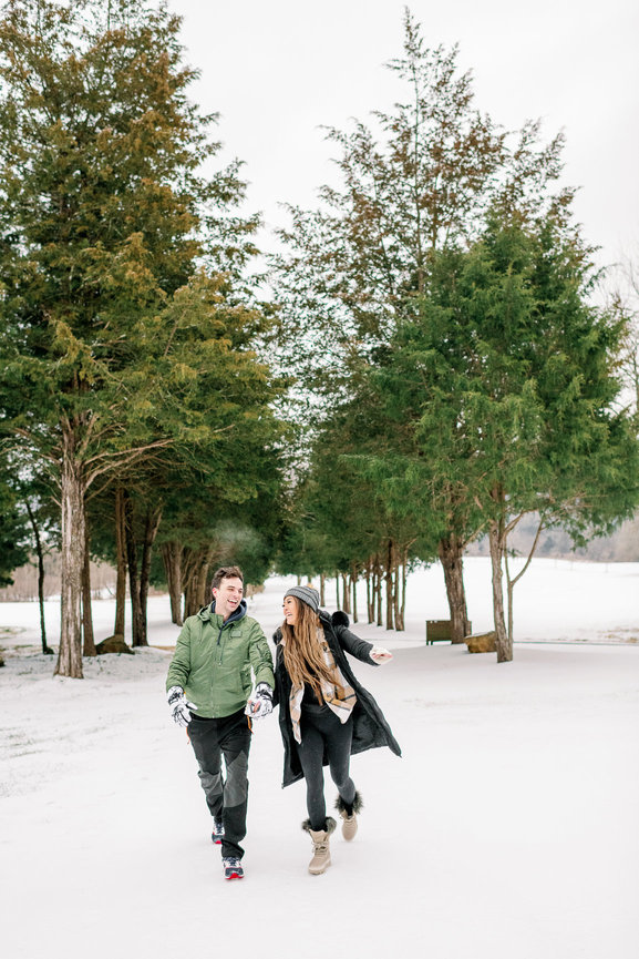 Couple running in the snow at their engagement shoot in Franklin, Tennessee. Engagement photography by Heather Durham.