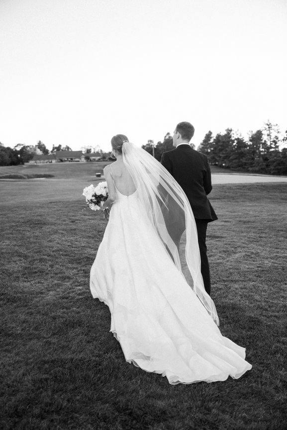 Black and white image of bride and groom walking on a mountaintop in North Carolina after their wedding ceremony. North Carolina wedding photography by Heather Durham.