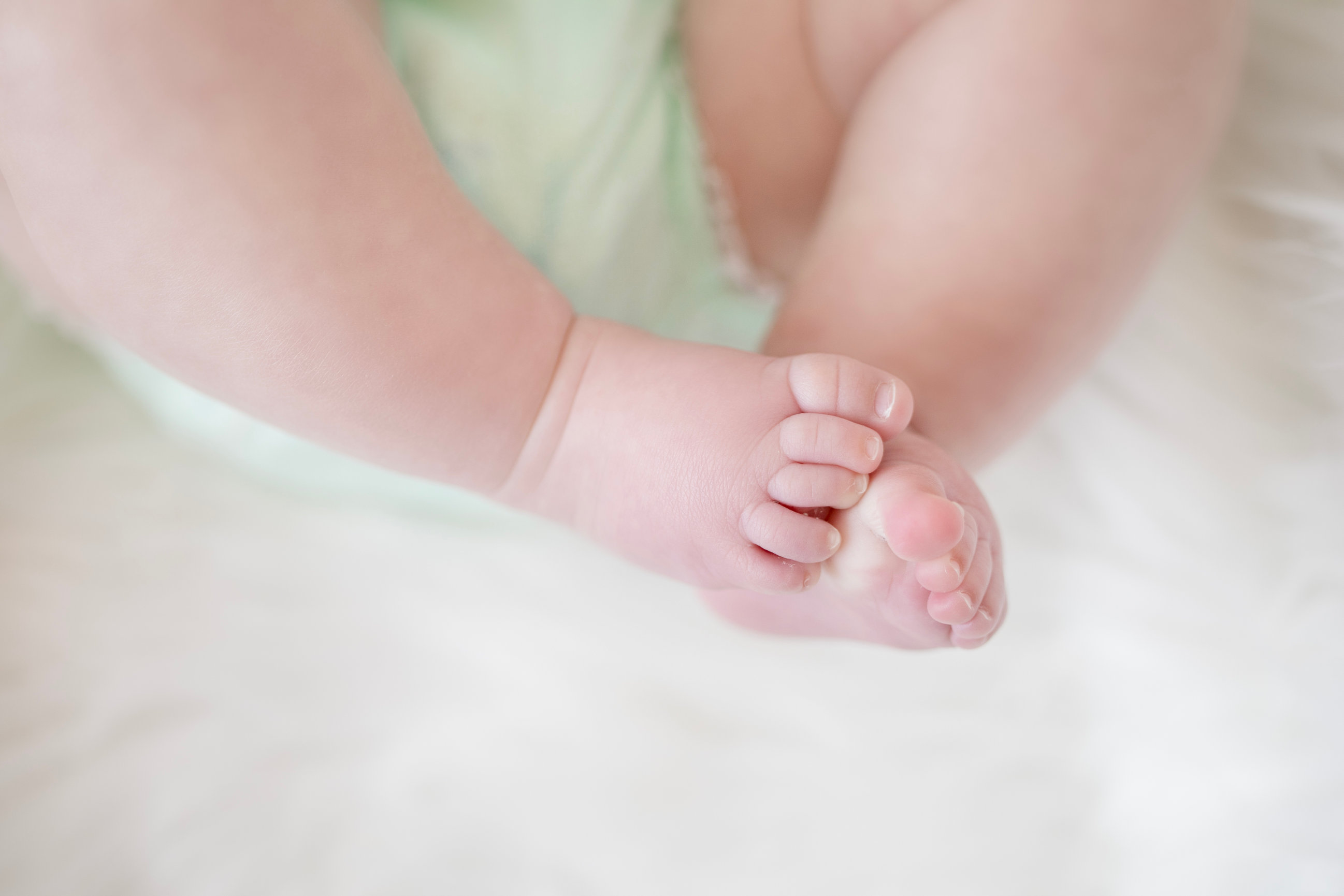 Tiny baby toes held gently between small hands
