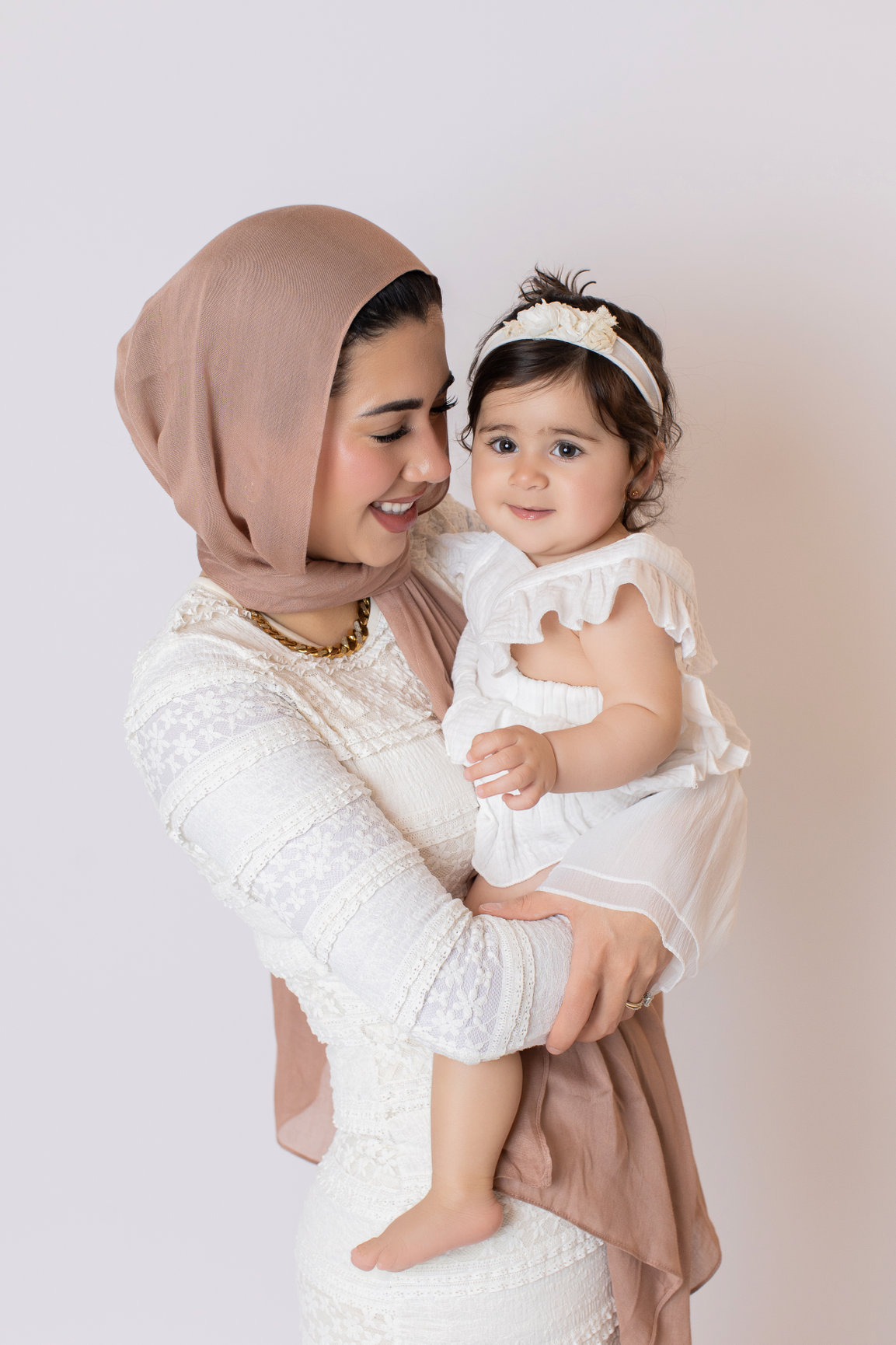 Mother holding her baby in coordinated cream outfits