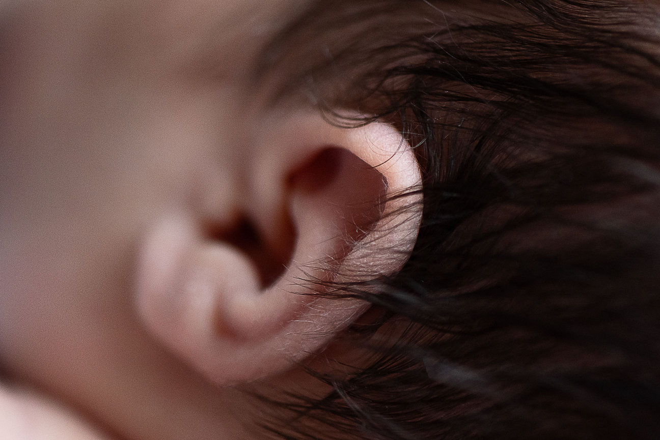 Close-up of a babys ear with soft, fine hair visible around the edges. The skin appears smooth and delicate, highlighting the small, intricate folds and structure of the ear—a tender moment captured in Elgin, Illinois.