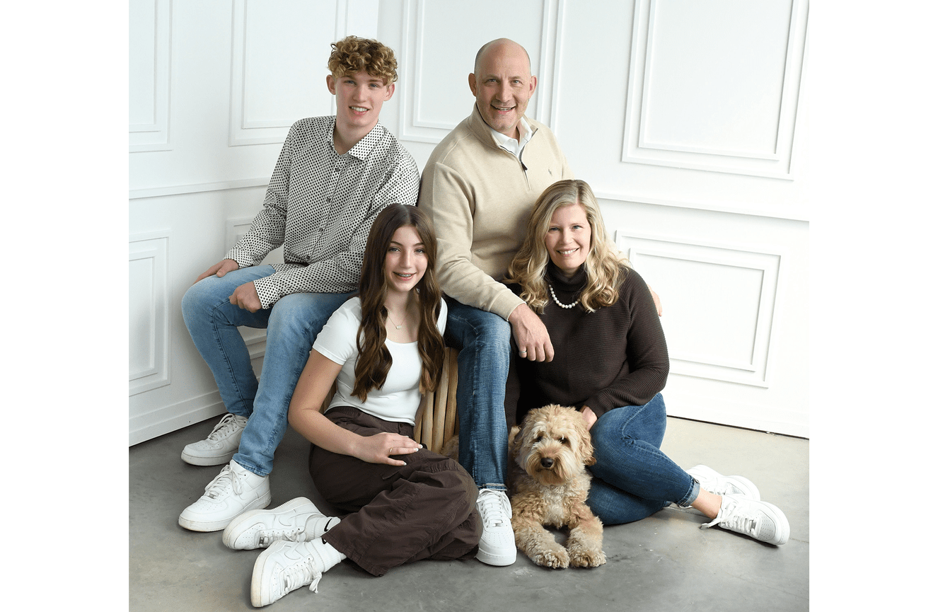 The Canadian Miller family wearing brown sweaters to match their beloved labradoodle dog.
