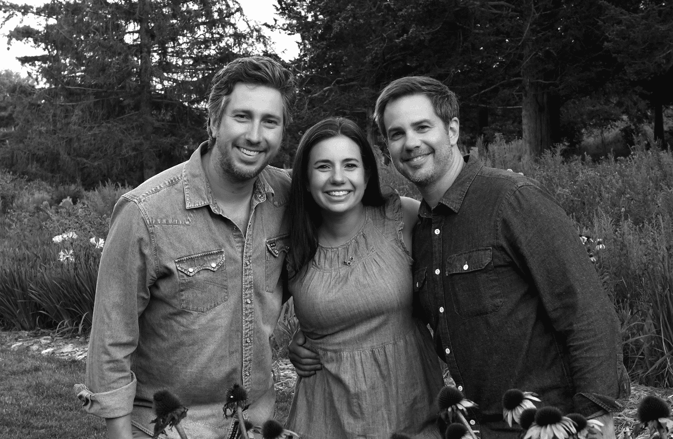 A black and white portrait of an adult woman and her two brothers standing in a field of flowers in Cedar Rapids, Iowa.