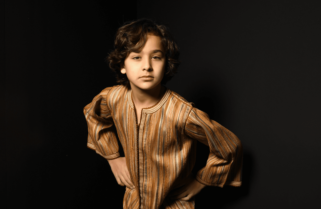 A young boy with thick tussled chestnut hair wearing a golden family heirloom robe.