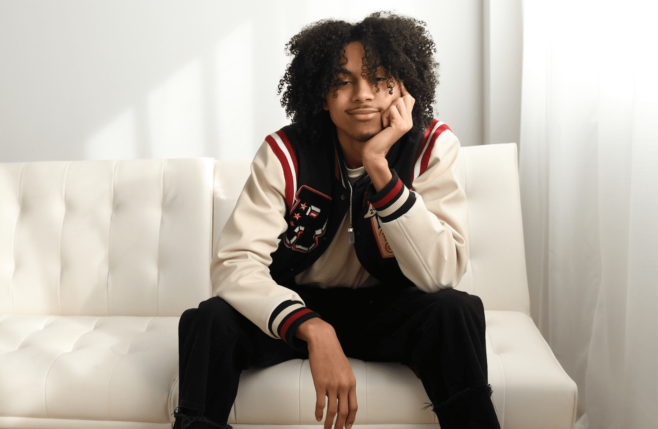 A teenager wearing his high school letter jacket poses pensively at Kliks Photography.