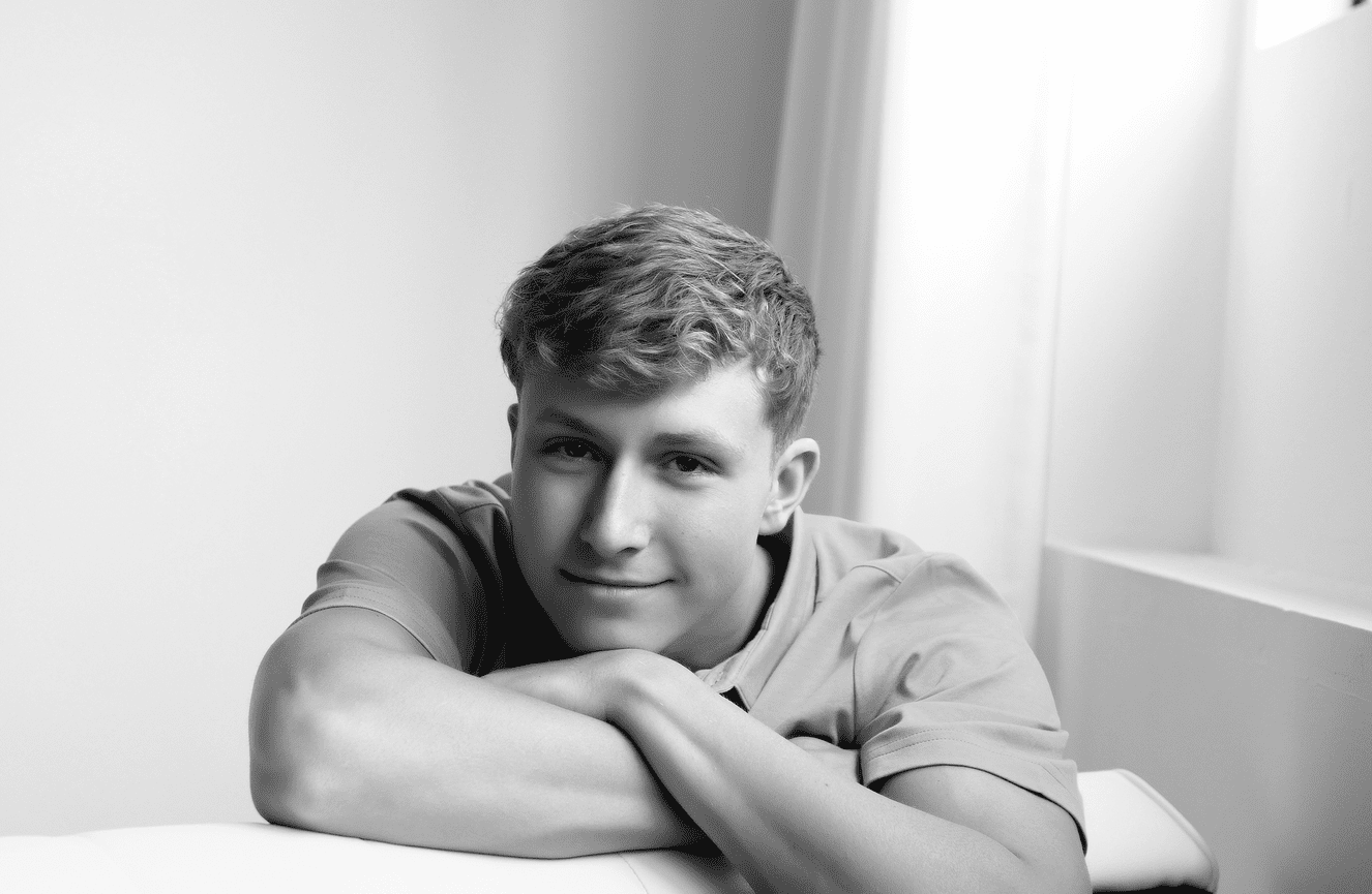 High school senior Cooper folding his arms over the back of a couch.
