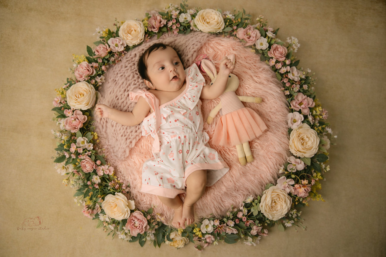 Baby lying on pink blanket surrounded by flowers