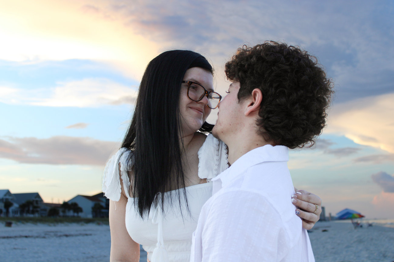 A couple standing close together by the ocean at sunset