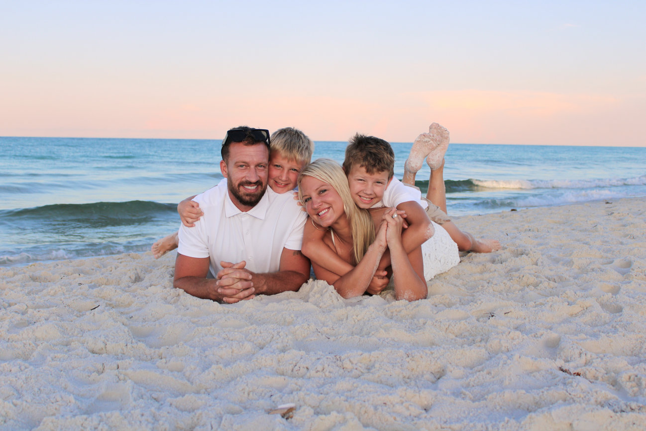 A family of three lying on the beach and smiling