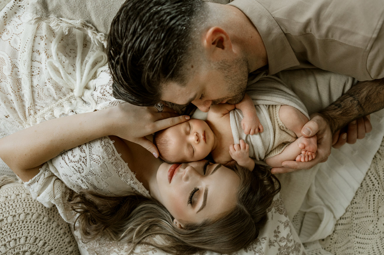 New parents gently cradling their newborn baby, creating a tender family moment together.