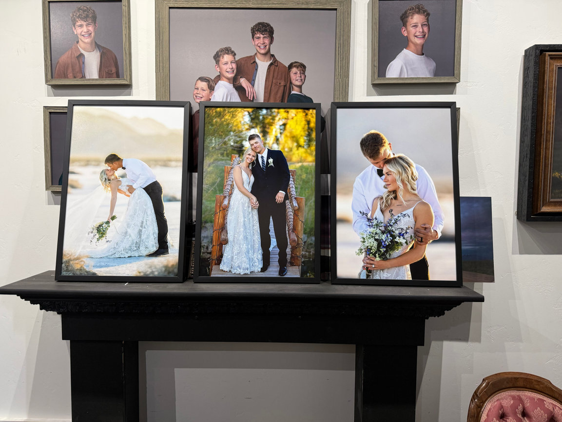 Framed wedding and family portraits displayed on a black mantel