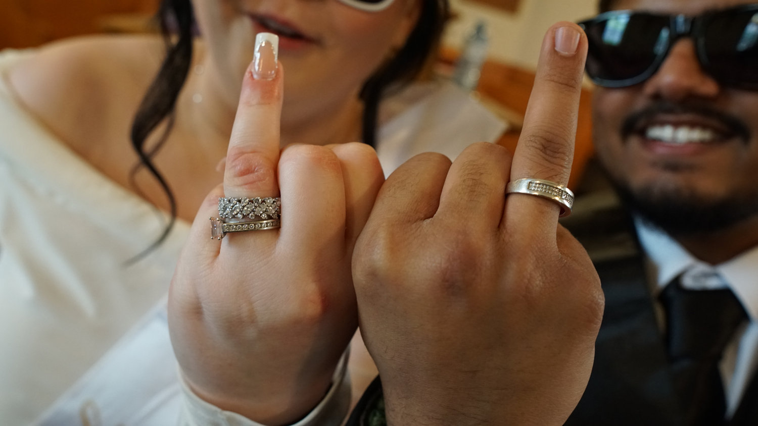 Bride and groom showing their wedding rings with crossed pinkies